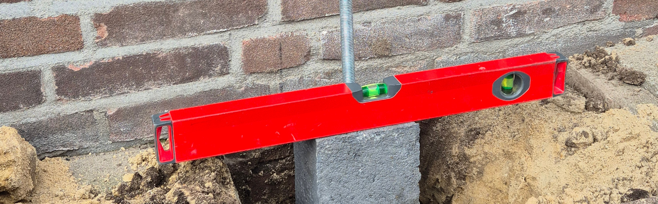 Betonpoer die waterpas staat als voorbereiding op het plaatsen van een overkapping